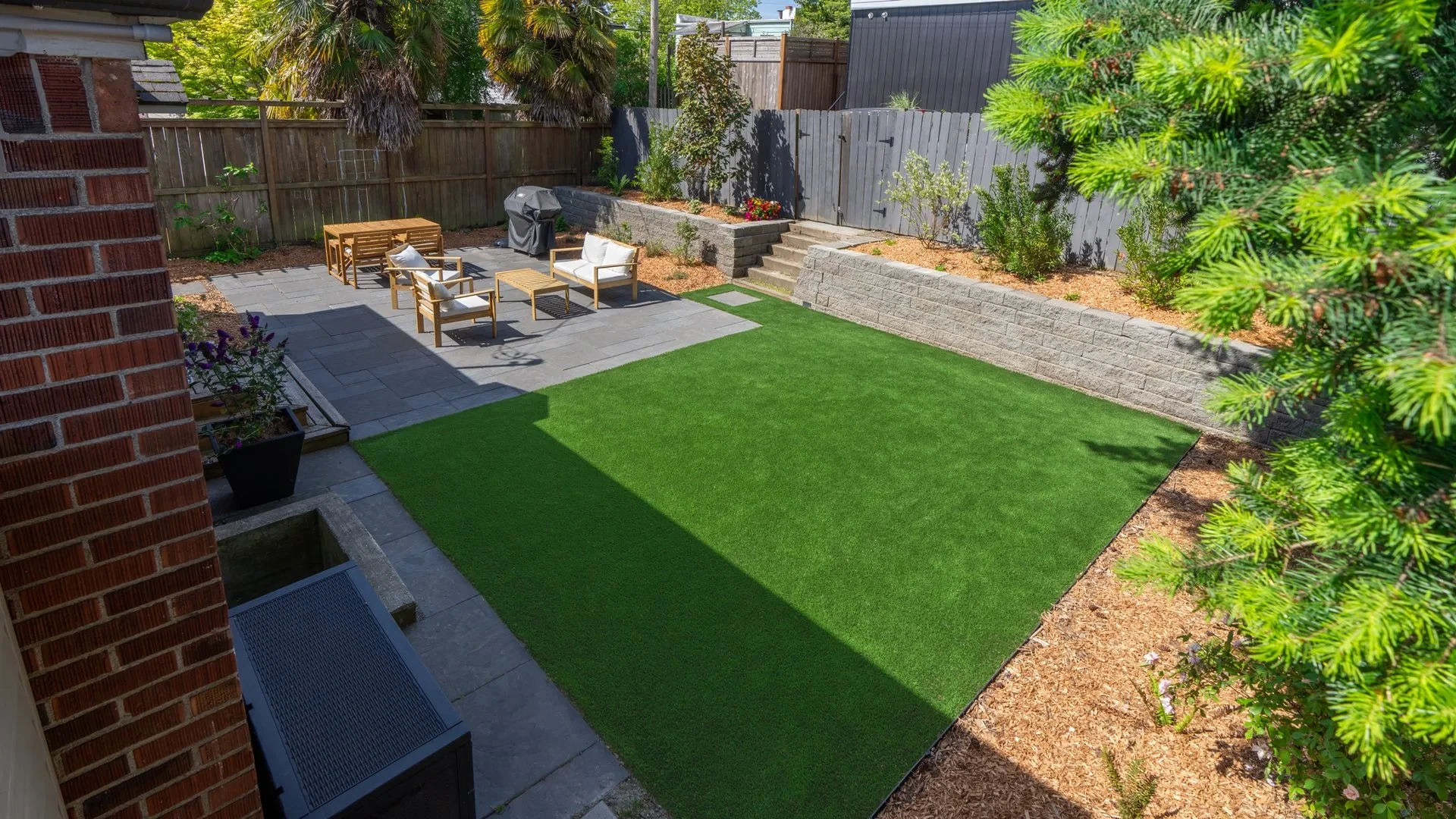 A compact turf backyard bordered by a patio and planted beds