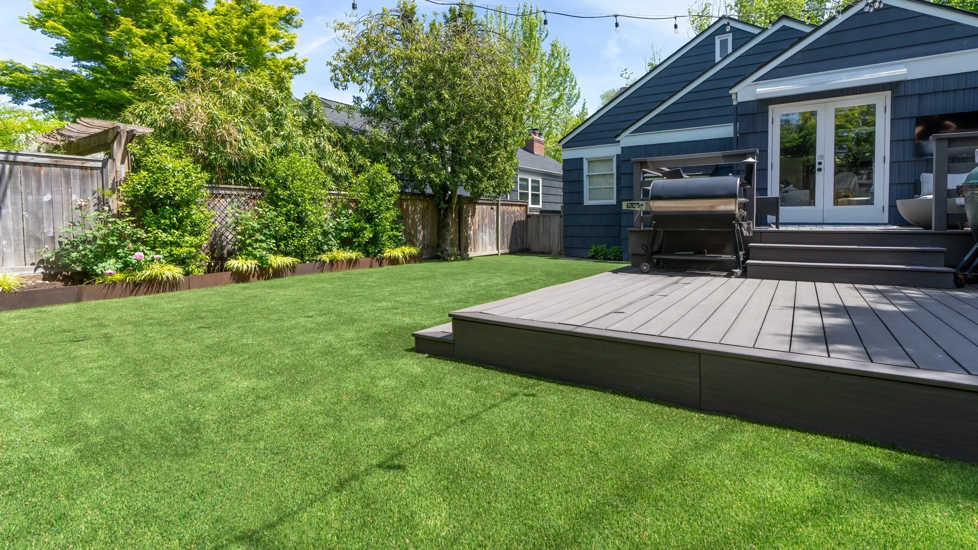 A turf lawn wrapping around a backyard deck